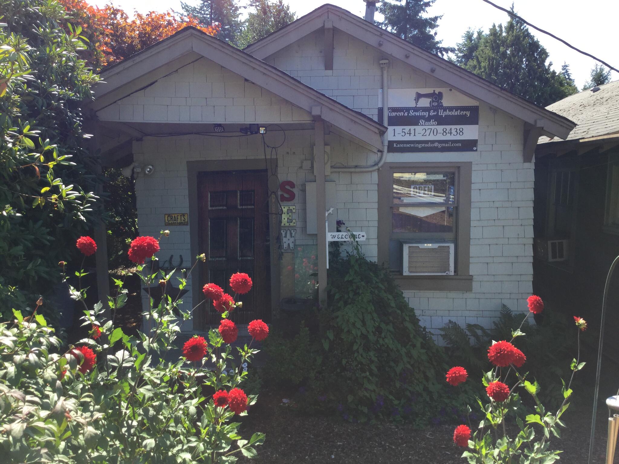 Karen’s studio photograph from its public profile, with sewing and upholstery sign and flowers outside